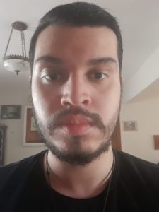 Retrato de Bruno Rondon: homem branco de cabelo curto escuro e barba e bigode ralos também escuros. Rosto ovalado, nariz largo e lábios grossos. Em uma fotografia tirada do pescoço para cima, ele aparece usando uma camiseta preta e sério, sem qualquer esboço de riso. No fundo, um ambiente que remete a uma casa, com alguns quadros na parede e um lustre no teto.